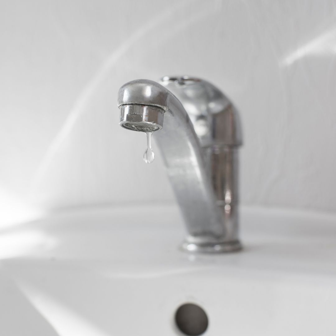 A drop of water falling from sink faucet.